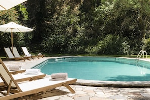 Un espace aménagé au bord de la piscine, avec des chaises longues et une piscine.