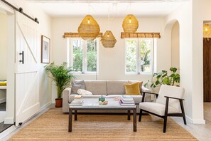 A cozy living room with a sofa, armchair, coffee table, and hanging rattan lamps. - A Hideaway Paradise by CadenzaLux (Cascais)