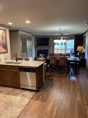Enjoy meals in the kitchen and dining area, featuring a dishwasher, granite countertop, wooden table, and outdoor views.