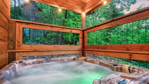Une cabane en bois dotée d’un bain à remous, le tout entouré d’une structure en verre.