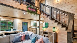 L’intérieur d’une maison en rondins moderne, avec un escalier, un canapé d’angle et un coin repas.