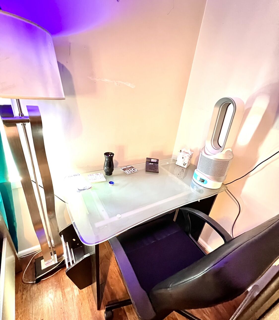 A small office space with a desk, chair, lamp, and various office supplies.