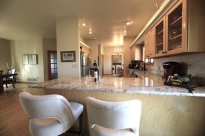 A kitchen with granite countertops, wooden cabinets, and a stainless steel refrigerator.
