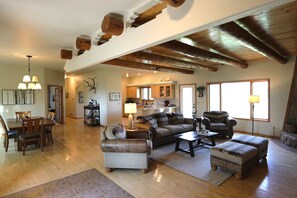 A spacious living area with a high ceiling, wooden beams, a dining area with a chandelier, and a kitchen in the background. - Mountain -Ranch Views! Near River Access! Fly Fishing. (Salida)