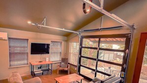 A modern living room with a sectional sofa, a coffee table, and a TV. There are large windows and a door leading outside. - NW Modern, River, Old Mill near Downtown (Bend)