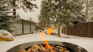 A snow-covered outdoor area with a fire pit containing burning wood. - NW Modern, River, Old Mill near Downtown (Bend)
