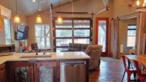 A spacious kitchen with a dishwasher, a dining area with a red table and chairs, and a gray sofa. - NW Modern, River, Old Mill near Downtown (Bend)