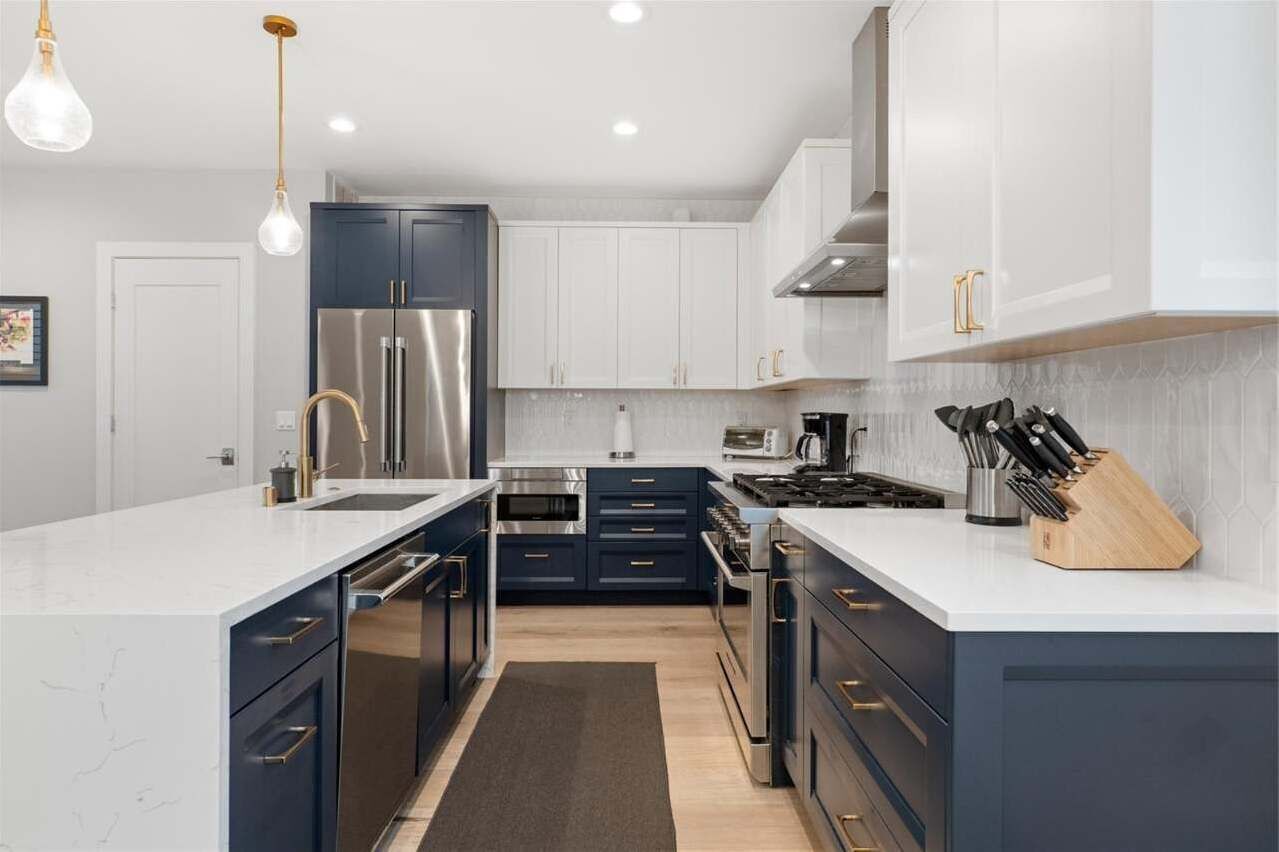 A modern kitchen with dark blue cabinets, stainless steel appliances, and a white countertop.