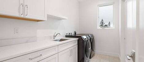 A modern kitchen with white cabinetry, a built-in sink, and a window with a view of trees.