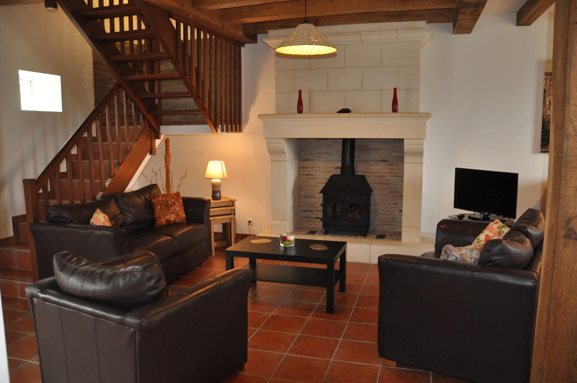 Una sala de estar con chimenea, sofás de cuero, una mesa de centro y un televisor.