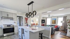 A modern kitchen with white cabinets, a built-in oven, and a central island with bar stools.