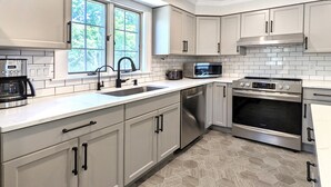 A modern kitchen with white cabinets, a stainless steel range, a microwave, and a dishwasher.
