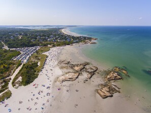 Zona costera con playa, estacionamiento, gente disfrutando y una vista despejada del océano.
