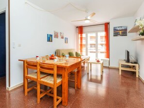 A dining area with a wooden table and chairs, a ceiling fan, a sofa, and a television on a stand. - Lovely apartment for 4 people with pool, WIFI, TV and terrace (Lloret De Mar)