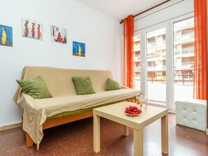 Un salon avec un canapé, une table sur laquelle on a disposé des fruits et des œuvres d’art accrochées au mur.