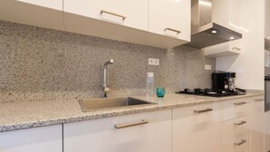 Una cocina moderna con encimera de granito, pileta de acero inoxidable y estufa negra.