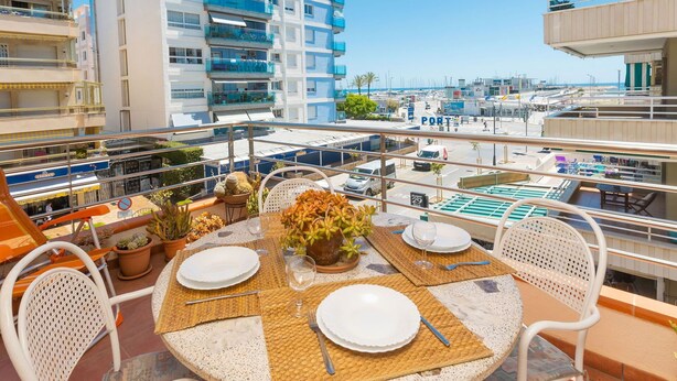 Una terraza en la azotea con una mesa lista para cenar, con vistas a un puerto deportivo y edificios.