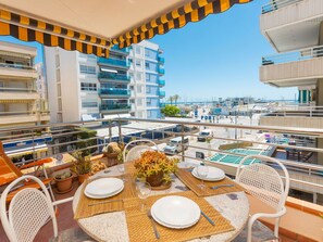Una terraza en la azotea con una mesa lista para cenar, con vistas a un puerto deportivo y edificios.