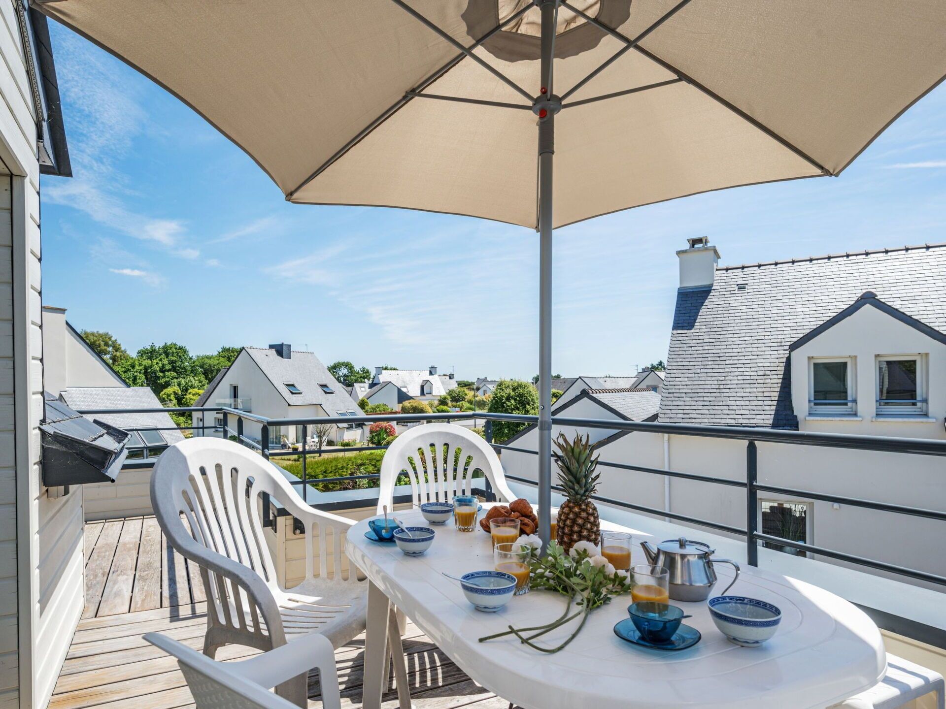 Een balkon met een tafel gedekt voor het ontbijt, inclusief kommen, glazen en een ananas.