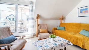 Un accogliente soggiorno con un divano giallo, una sedia in legno e un tavolo con una tovaglia a motivi di pesce.