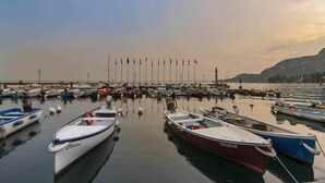 A marina with numerous boats docked, a lighthouse in the background, and a calm sea. - Residence Florida B10 - 200m from the lakefront (Lazise)