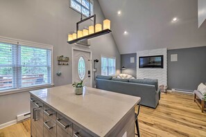 A modern kitchen with a large island, a grey sofa, and a fireplace. - Near Lakes & Resorts: Pet-Friendly Long Pond Abode (Long Pond)