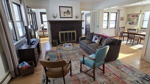 A spacious living room with a fireplace, a sofa, a coffee table, and a dining area in the background. - Downtown Hibbing, 3 bd, 1 bath home with garage (Hibbing)