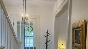 A hallway with a wooden staircase, a door with glass panels, a coat rack, a lamp, and a framed picture on the wall. - Downtown Hibbing, 3 bd, 1 bath home with garage (Hibbing)