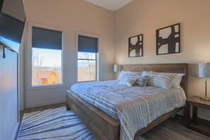 Una camera da letto con un letto di legno, due finestre con persiane, un tappeto e due opere d'arte appese alle pareti.