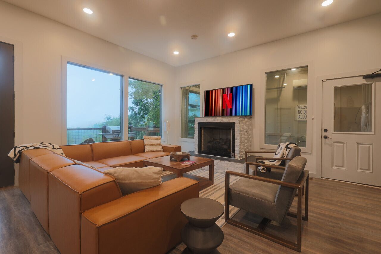 A modern living room with a sectional sofa, a fireplace, and a large window offering a view.