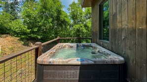 Un bain à remous sur une terrasse en bois, avec une maison en bois en arrière-plan.