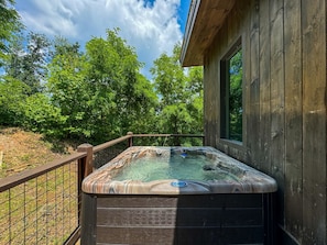 Un jacuzzi en una terraza de madera con una casa de madera al fondo.