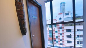 A room with a large window, a wooden door, and a wall-mounted sculpture. - Q Collection @ Macalister(formerly know as Apple Hotel Penang)  (George Town)