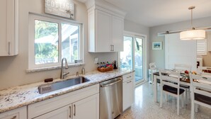 A modern kitchen with white cabinetry, a stainless steel dishwasher, and a granite countertop.