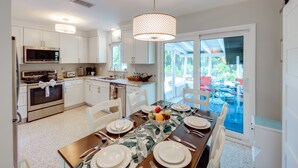 A modern kitchen with white cabinetry, stainless steel appliances, and a dining area with a table set for four.