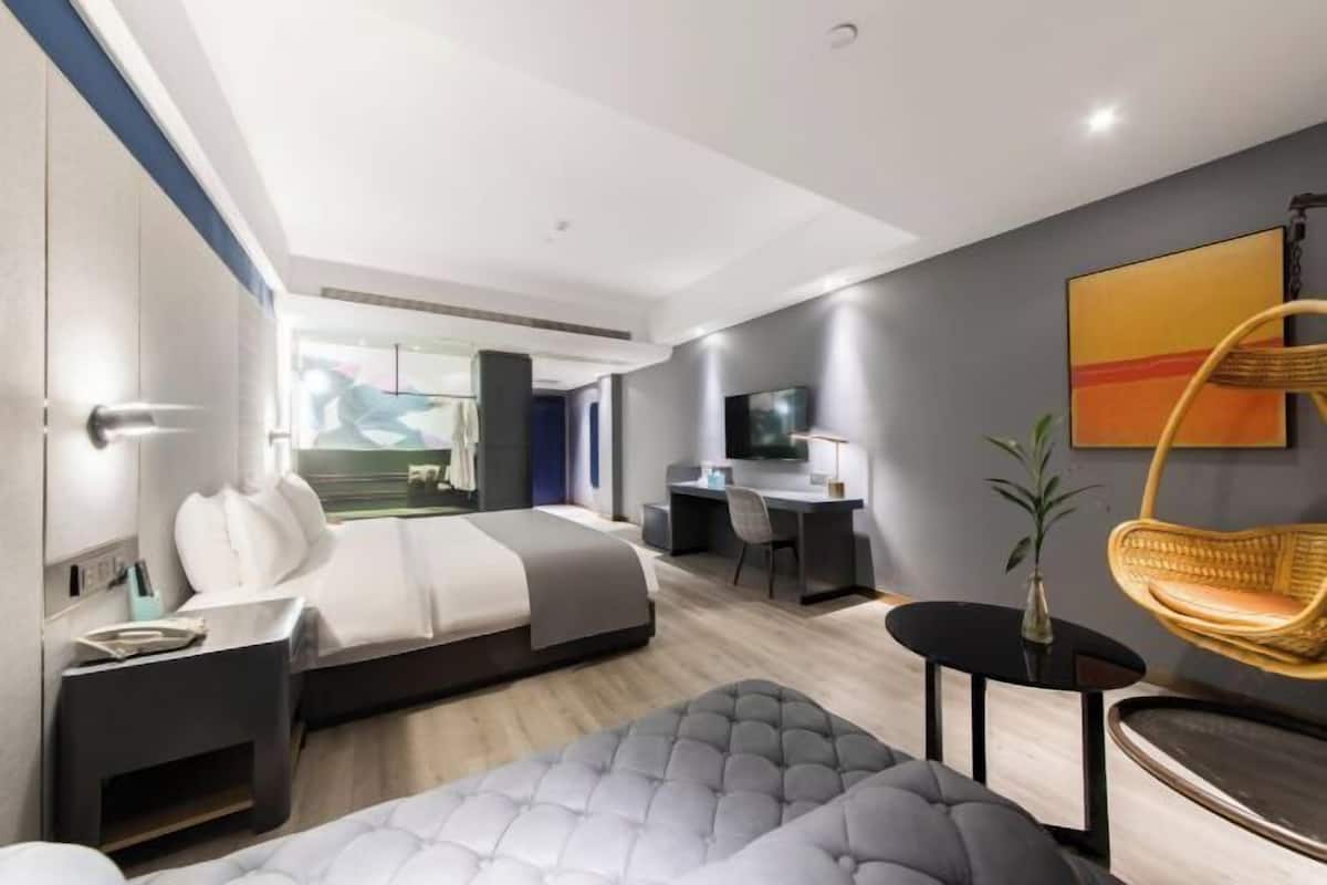 Ein modernes Hotelzimmer mit Bett, Schreibtisch und Sitzecke.