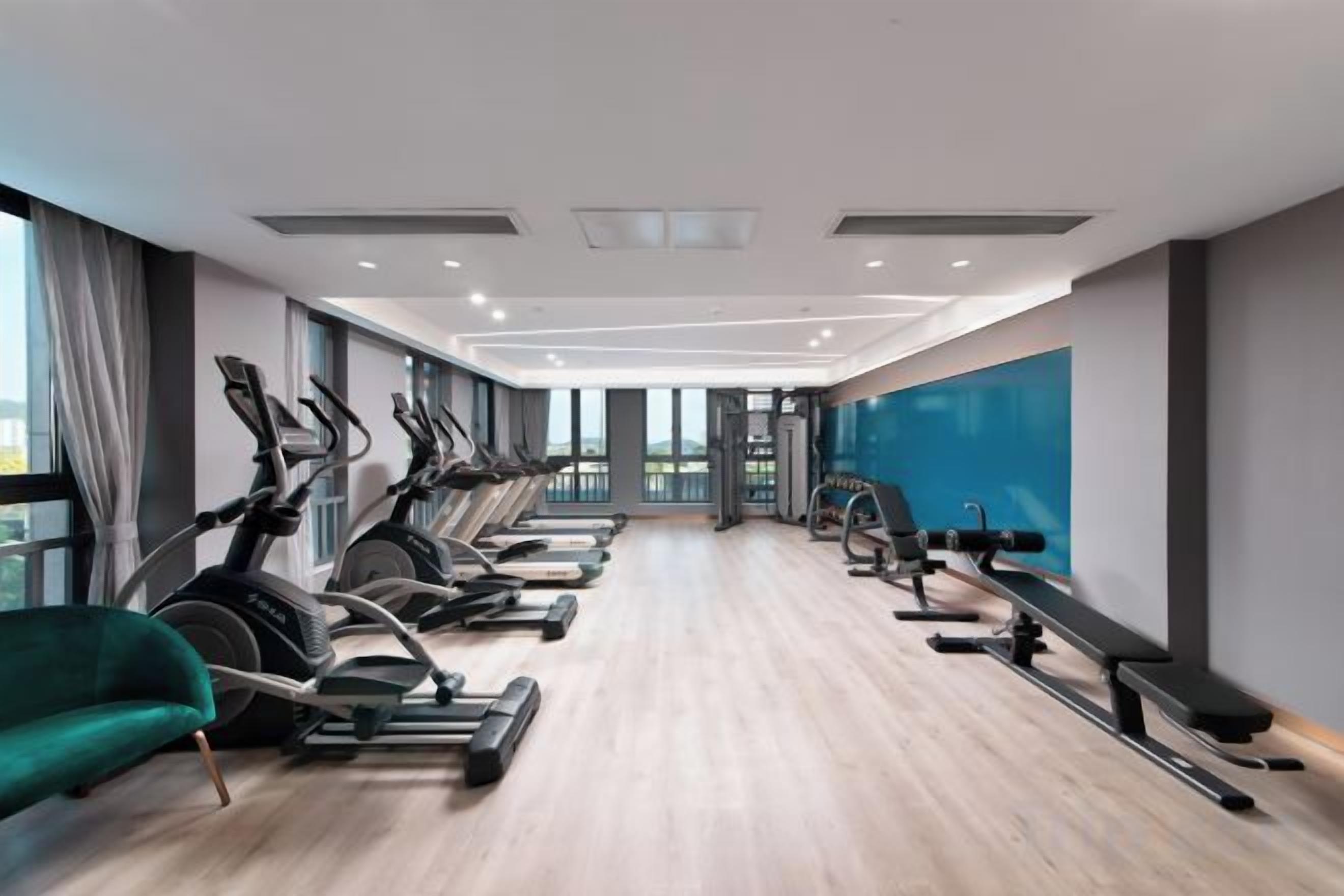 A gym with exercise equipment, large windows, and a modern interior design.