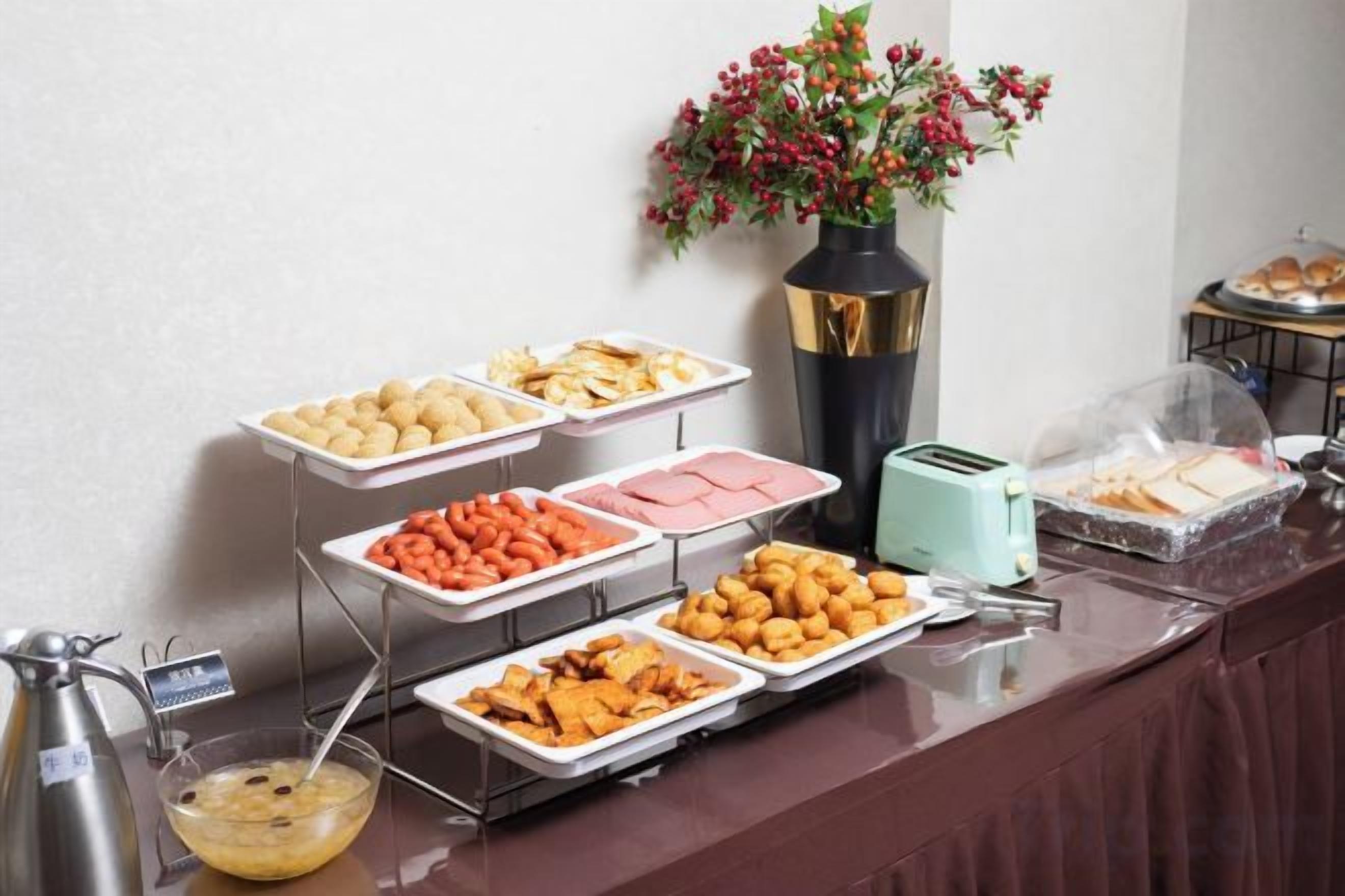 A buffet with various food items, a vase with flowers, and a toaster on a counter.