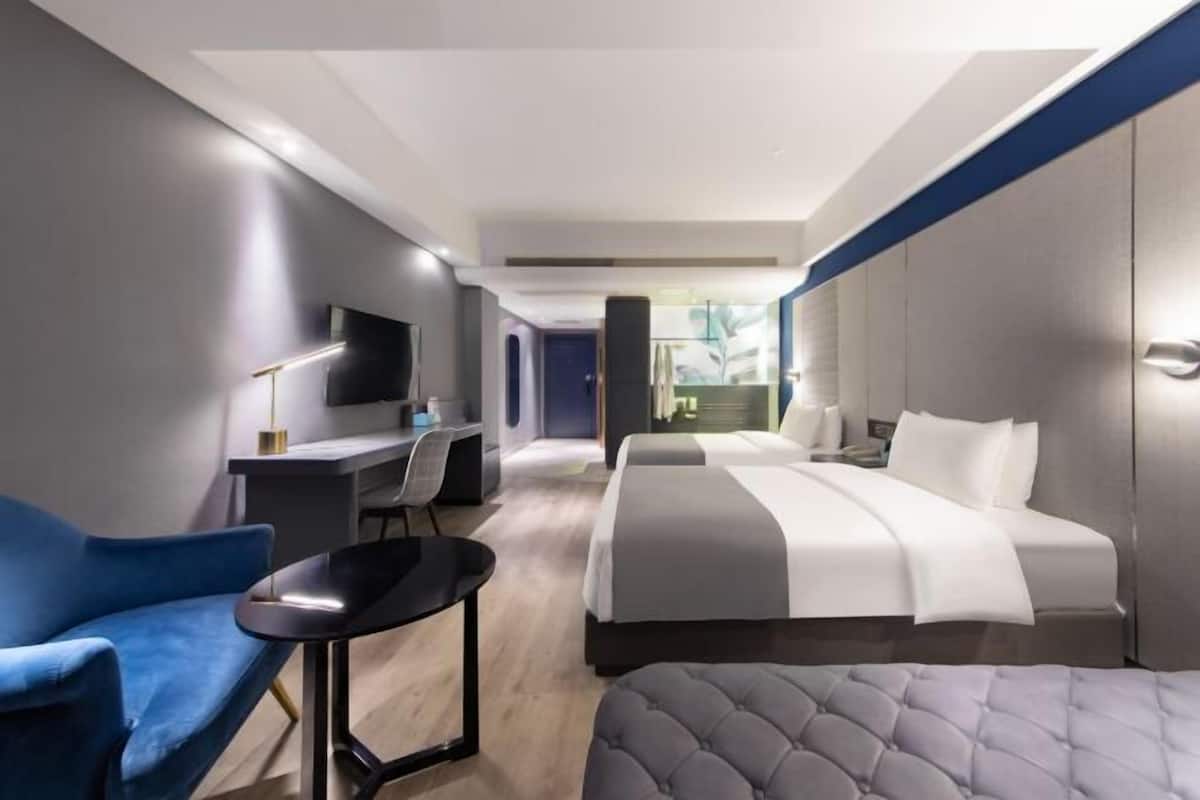 Ein modernes Hotelzimmer mit einem Bett, einem Schreibtisch, einem Sessel und einem Fernseher.
