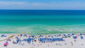 A beach with numerous umbrellas and sun loungers, a sandy shore, and a clear blue sea. - PET FRIENDLY! GREAT VIEWS! UPDATED FURNISHINGS! BCH SRVC INCL!!! (Panama City Beach)
