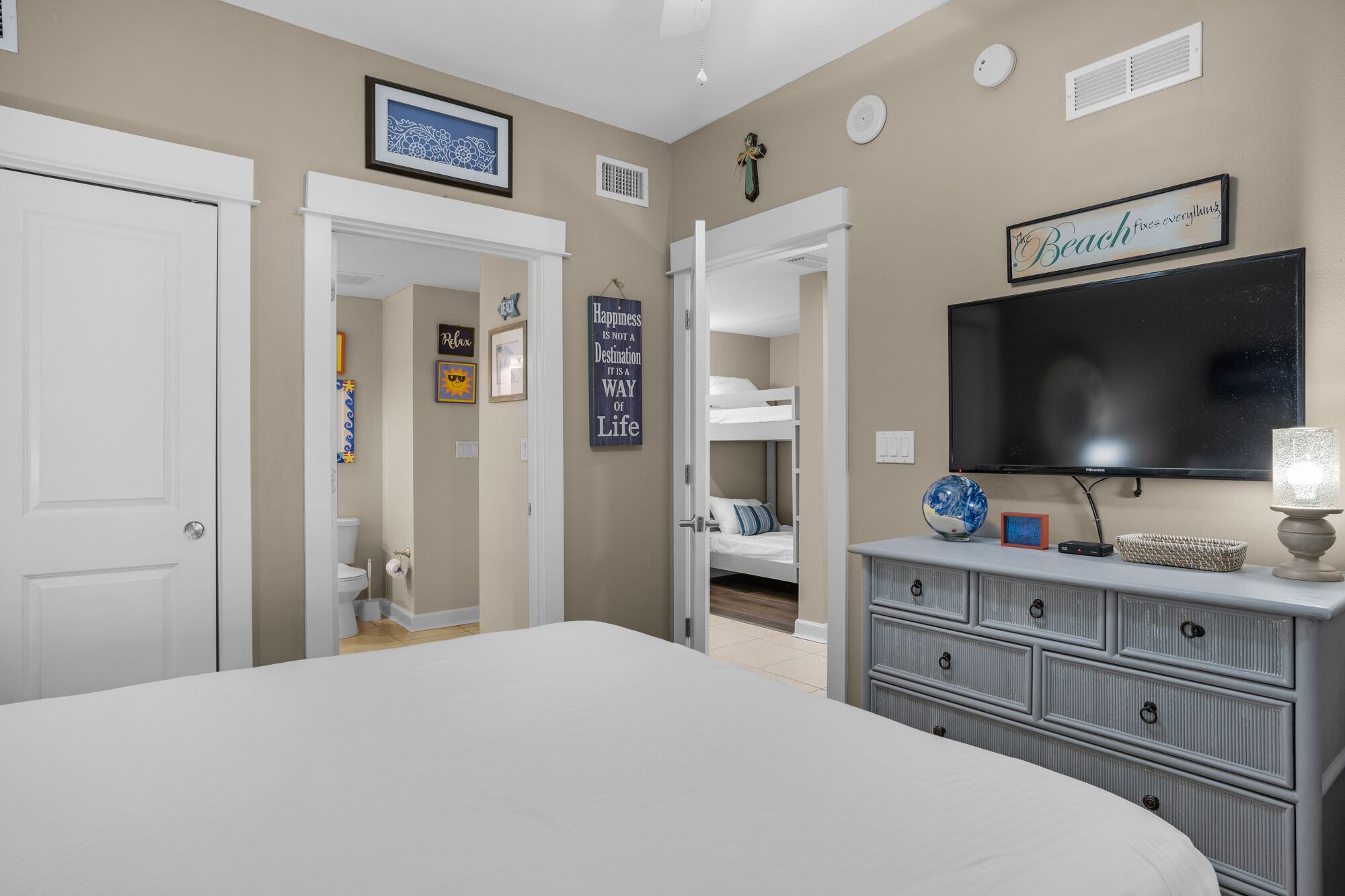 Un dormitorio con una cama grande, un aparador, una televisión y una puerta que da a un baño.