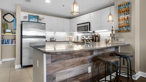 A modern kitchen with a central island, stainless steel appliances, and hanging pendant lights. - PET FRIENDLY! GREAT VIEWS! UPDATED FURNISHINGS! BCH SRVC INCL!!! (Panama City Beach)