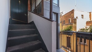 A staircase leading to a dark wooden door, adjacent to a white wall and a balcony with a black railing. - Spectacular attic with private terrace in central Rome - Wifi, Heating, A/C (Roma)
