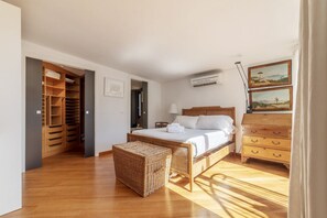 Ein Schlafzimmer mit einem hölzernen Bett, einer Korbschwamm-Truhe, einem Kleiderschrank und einer Kommode.