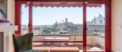 A room with a large sliding glass door leading to an outdoor terrace with a table and chairs.