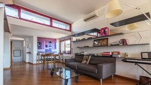 A spacious living area with a glass coffee table, a sofa, and a dining table with chairs. There are bookshelves and a keyboard on a stand. - Spectacular attic with private terrace in central Rome - Wifi, Heating, A/C (Roma)