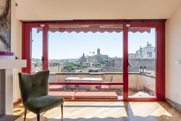 A room with a large sliding glass door leading to an outdoor terrace with a table and chairs.