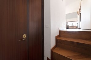 Eine Holztreppe führt zu einem Balkon mit Blick auf ein Gebäude.