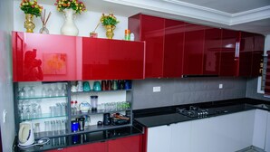 A modern kitchen with red cabinets, a black countertop, and various kitchen appliances. - Beautiful 4-Bedroom House Located in Abuja (Abuja)