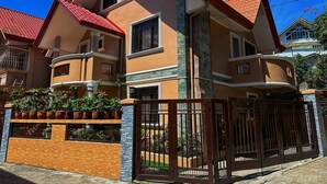 A multi-story house with a red-tiled roof, a stone chimney, and a gated entrance. - My Home in Baguio City (Baguio City)